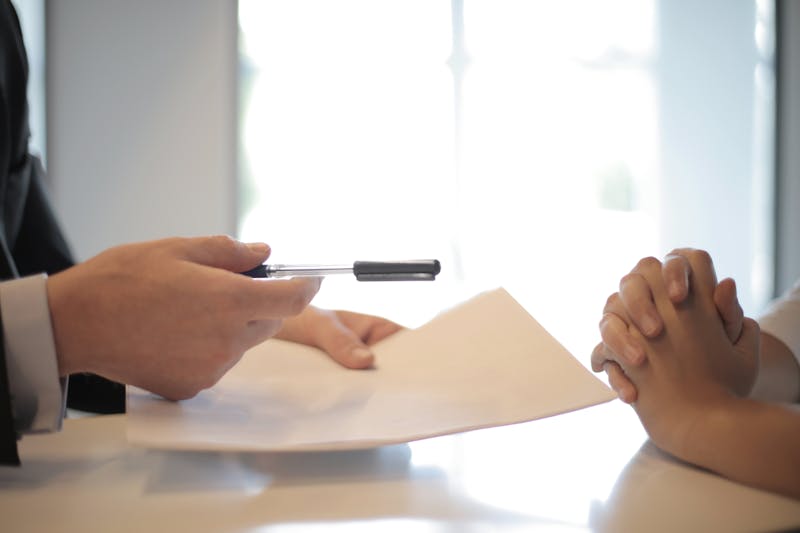 Professional handing document to employee at desk